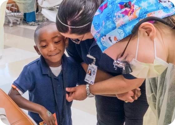 Two providers help a smiling young child. 