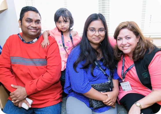 A young girl and her family smile in a waiting room.