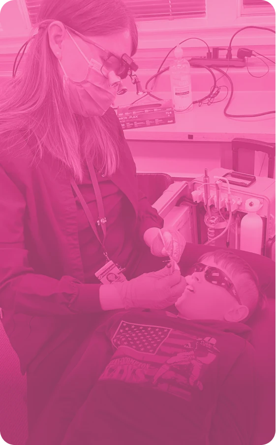 A young boy gets a dental exam from a female provider.