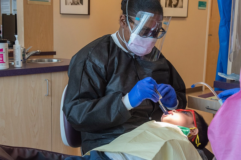 Dental hygienist doing teeth cleaning on young boy.