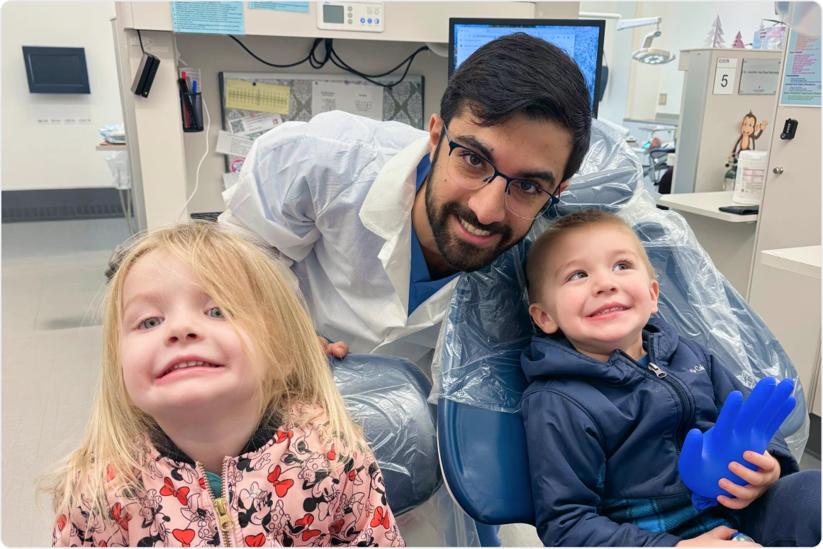 A dental provider and two young children smiling in a dental clinic setting
